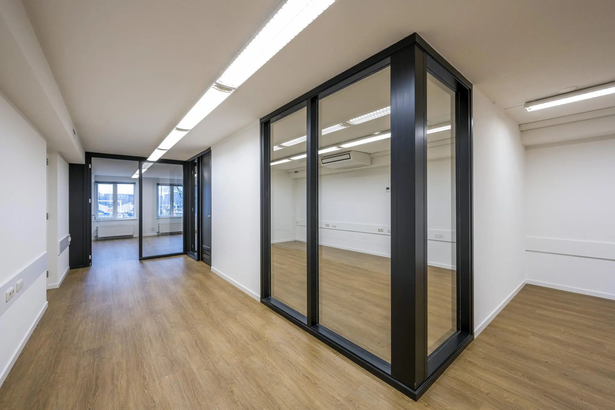 Modern gerenoveerde kantoorruimte aan de Prins Hendrikkade met glazen wanden en houten vloer.